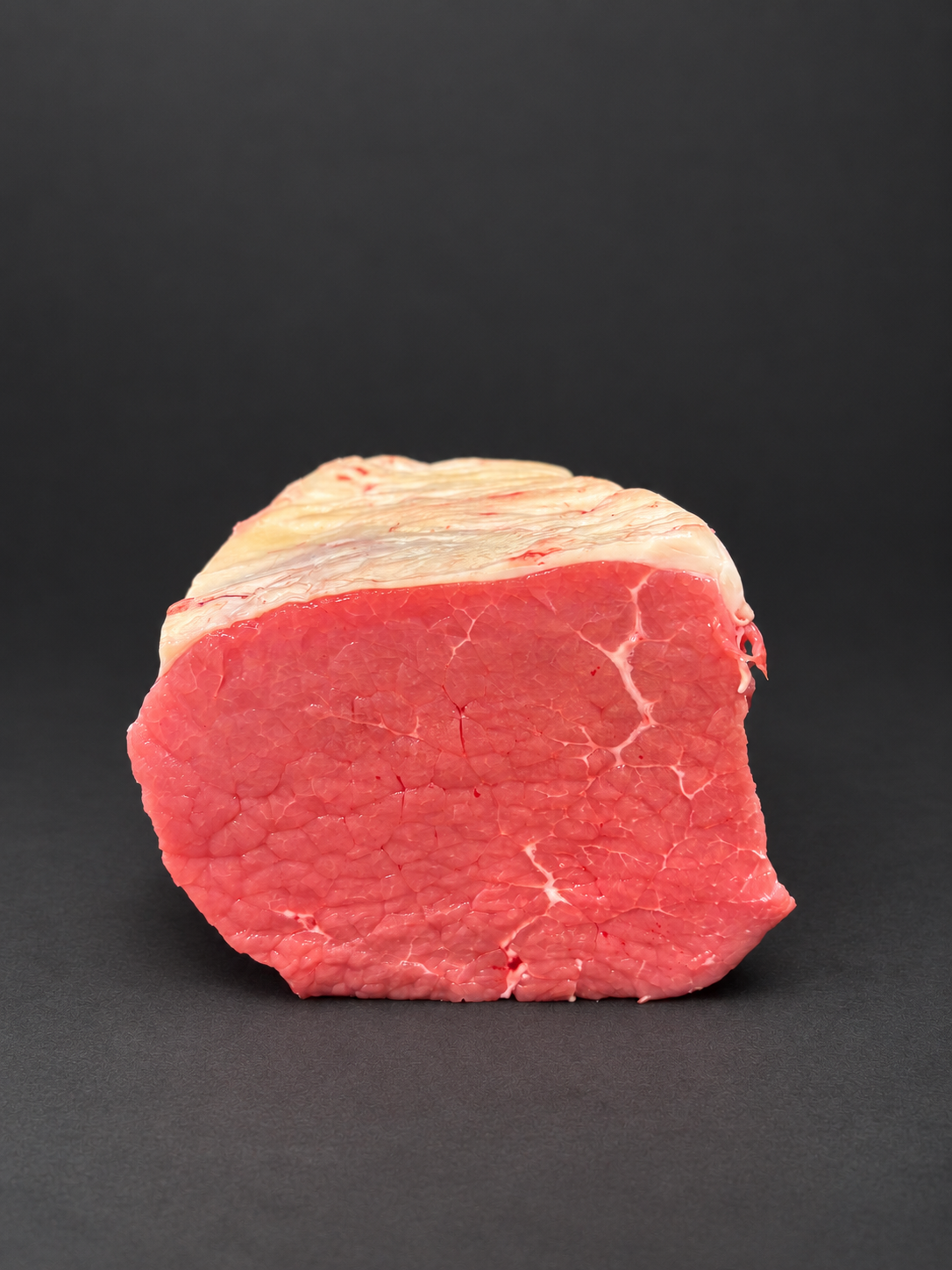 Front view of beef roasting joint on a smooth charcoal background