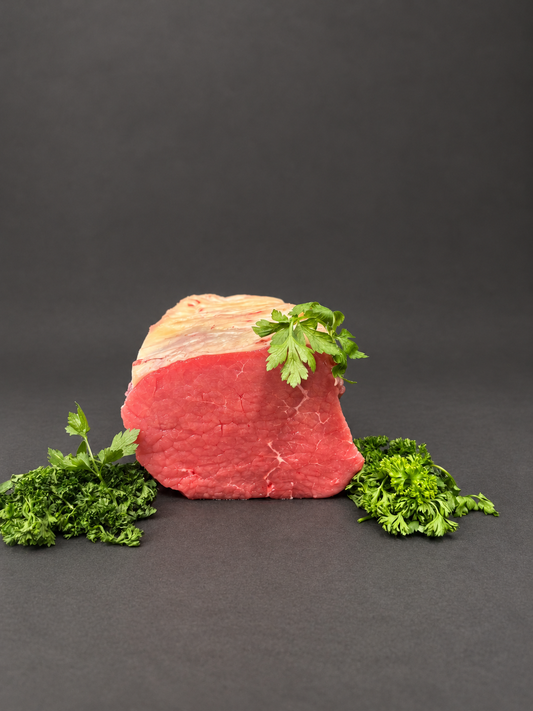 Beef roasting joint with parsley on a smooth charcoal background